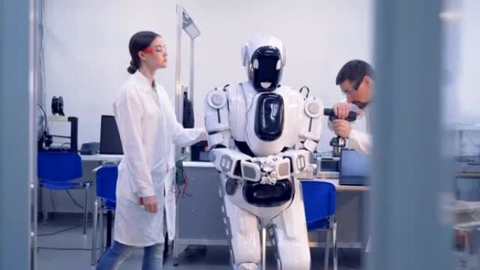 两名工程师正在检查和修复类似人类的机器人