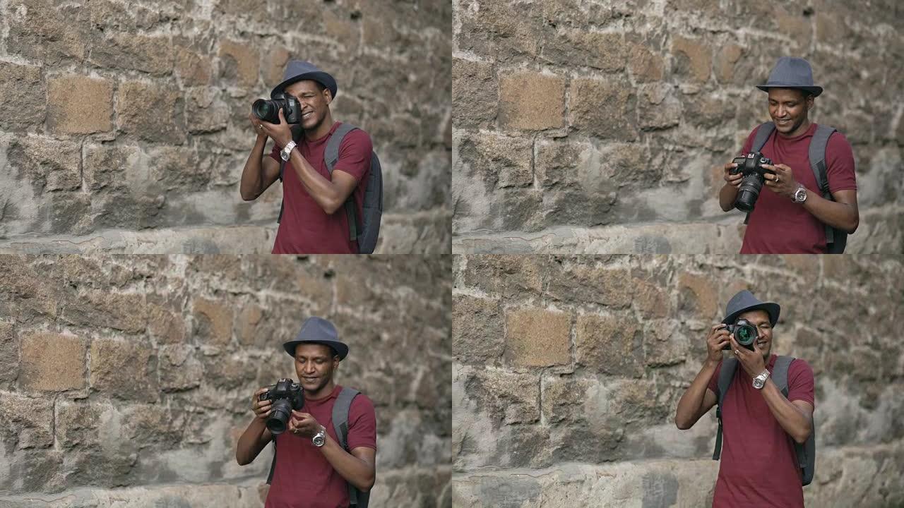 非裔美国快乐游客在他的单反相机上拍照。站在欧洲著名建筑附近的年轻人