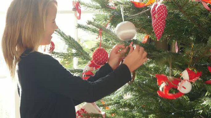 年轻女孩在圣诞树上悬挂装饰品