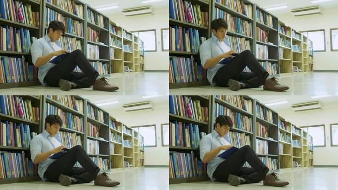 男大学生坐在图书馆的地板上看书