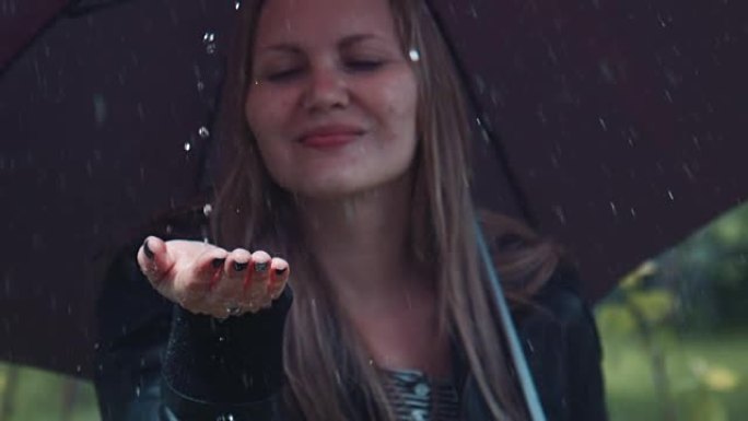 金发女人在黑色扭动伞下享受雨水