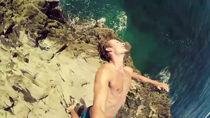 POV慢动作悬崖跳跃后空翻。健壮的年轻人从悬崖上跳入大海。
