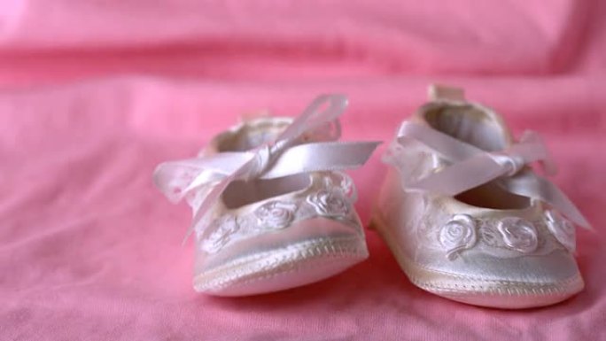 婴儿短靴落在粉红色的毯子上