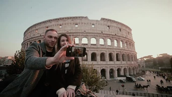 年轻的幸福夫妇在智能手机上自拍照片。意大利罗马罗马斗兽场附近有吸引力的男人和女人