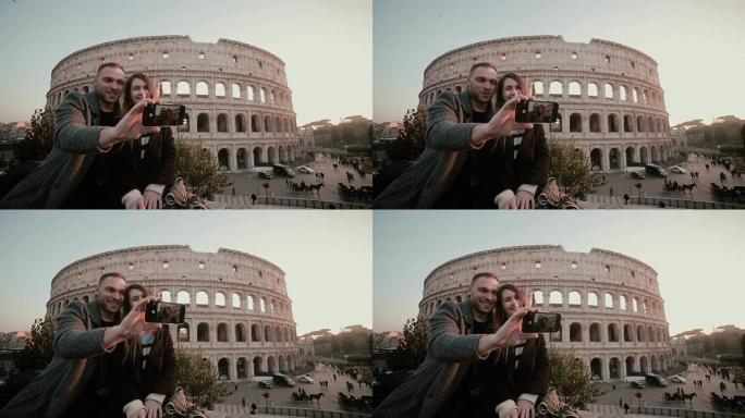 年轻的幸福夫妇在智能手机上自拍照片。意大利罗马罗马斗兽场附近有吸引力的男人和女人