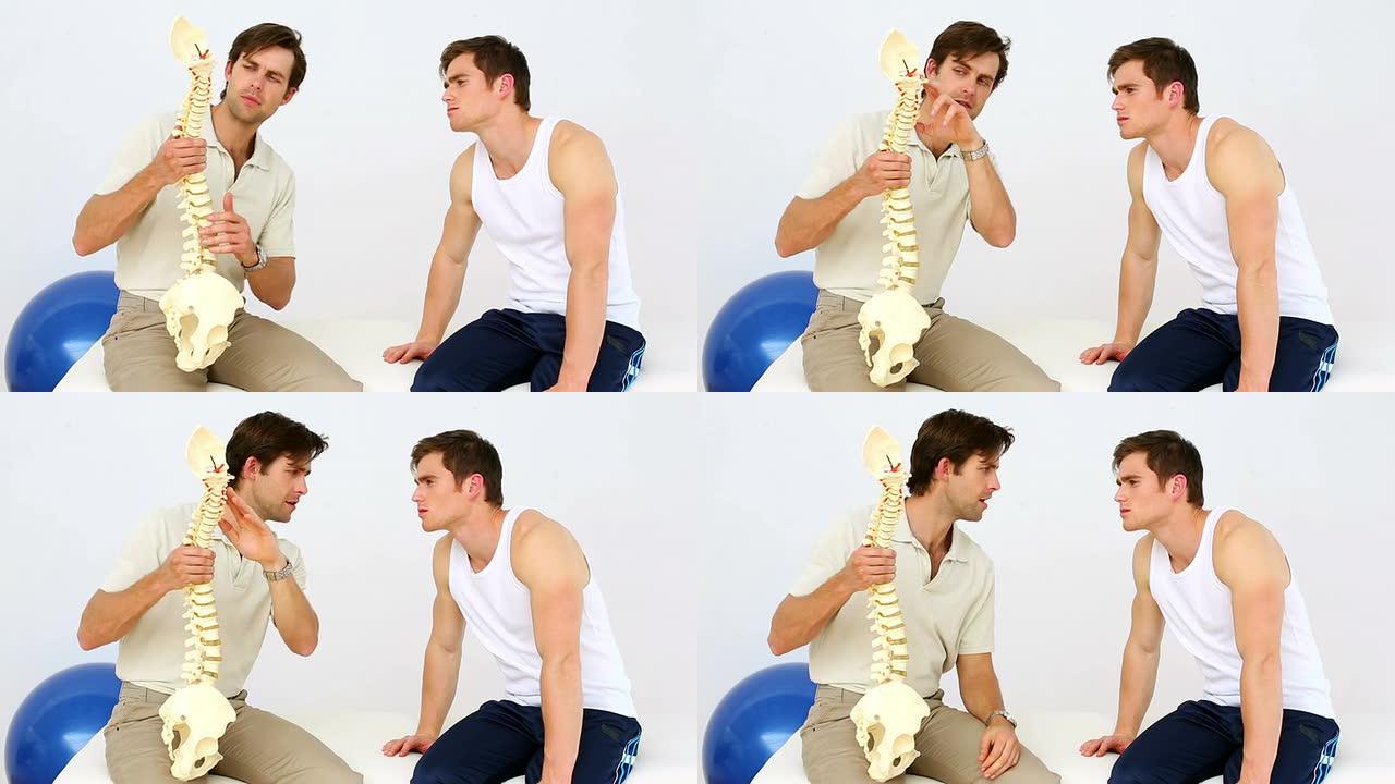 物理治疗师与患者交谈，向他展示脊柱模型