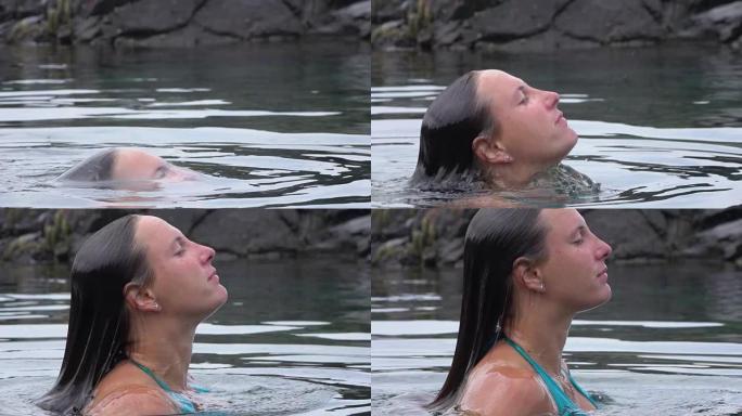 慢动作: 穿着比基尼的年轻女子在水下升起，浮出水面。