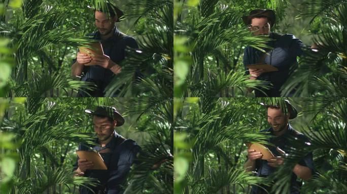 在丛林森林中使用平板电脑的帽子冒险家。