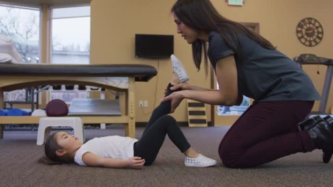 物理治疗师伸展一个年轻女孩的腿