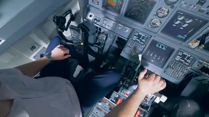 一名飞行员把手放在驾驶舱的杠杆上，靠近。
