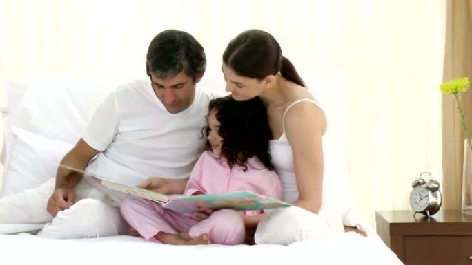 细心的父母和他们的女孩一起看书