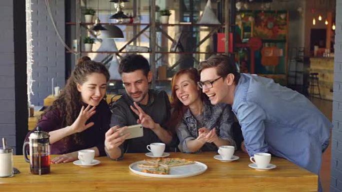 年轻人拿着智能手机进行视频聊天，看着网络摄像头在尼斯咖啡馆的桌子上与朋友聊天。现代交流和友谊概念。