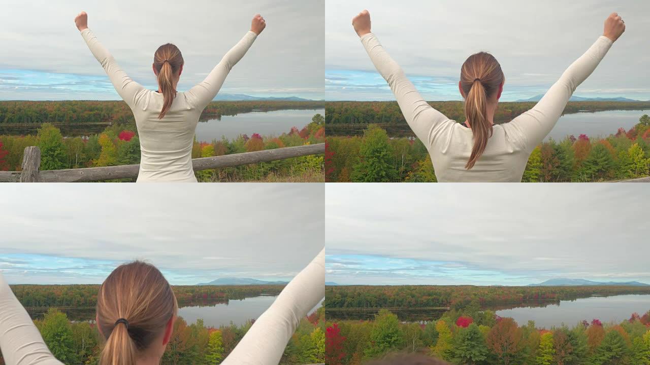 特写: 年轻女子在秋天的湖泊和森林的视点上伸出双臂