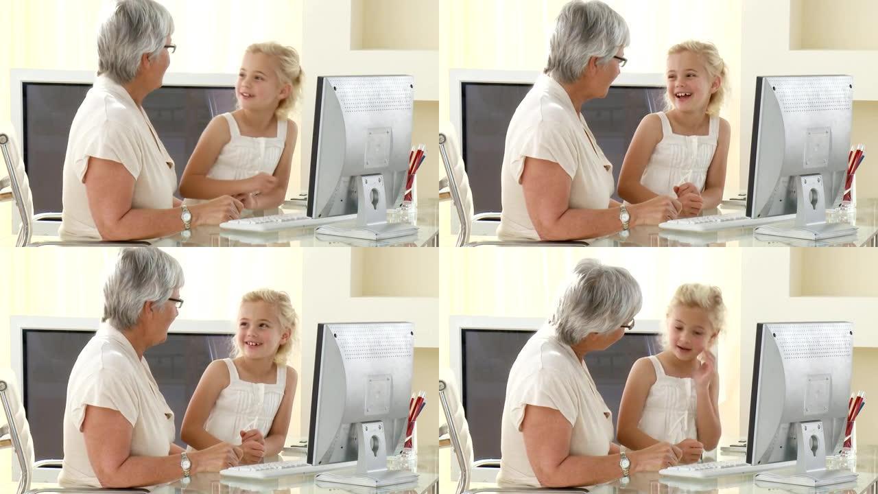 快活的高级妇女与孙女一起使用计算机