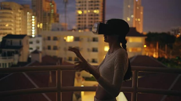 屋顶露台上的年轻女子使用虚拟现实耳机，晚上有虚拟现实体验