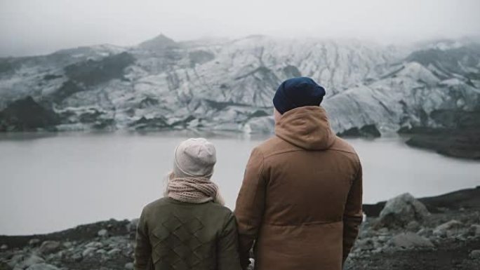 站在冰泻湖的年轻夫妇的后视图。旅行男女一起探索冰岛