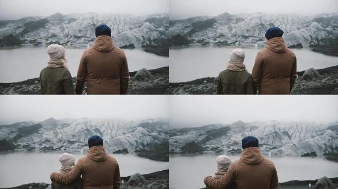 站在冰泻湖的年轻夫妇的后视图。旅行男女一起探索冰岛