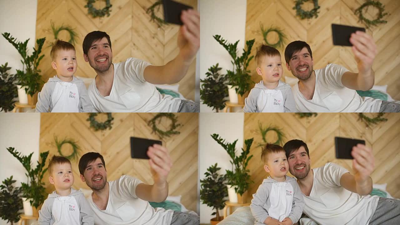 年轻的微笑父亲和儿子在床上用智能手机相机拍照