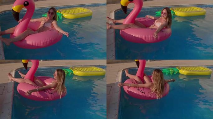 漂浮在游泳池里的粉红色火烈鸟上的年轻女子