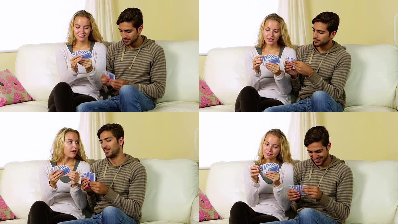 可爱的快乐夫妇在沙发上一起玩牌