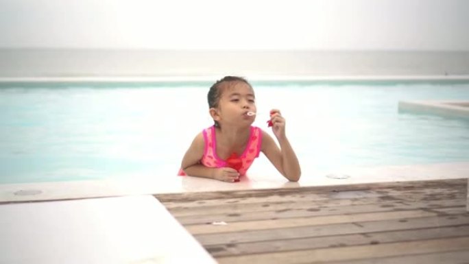 一个可爱的快乐的年轻女婴婴儿在游泳池边放松，天空。