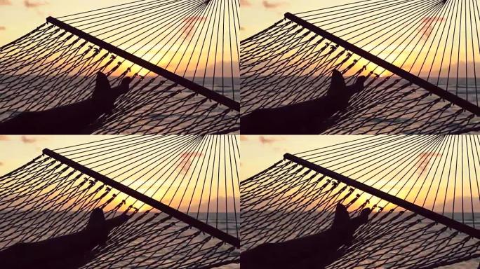 双脚在日落时分在大海之间摆动。温暖的Instagram色调