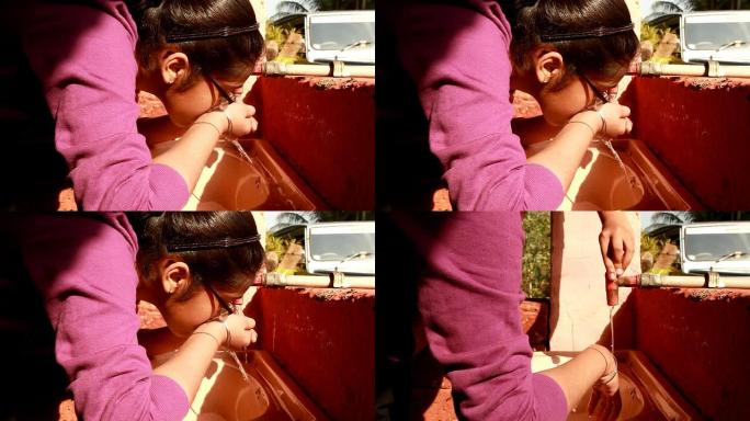 亚洲印度青少年女孩从水龙头喝水