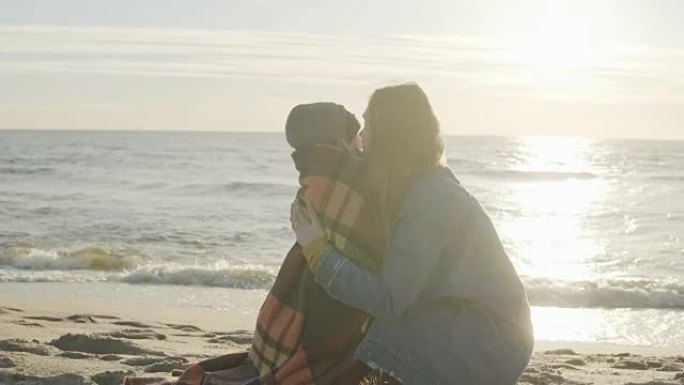 阳光明媚的日子，家人在沙滩上度过时光。母亲拥抱，坚持她可爱的小儿子。一起快乐时光