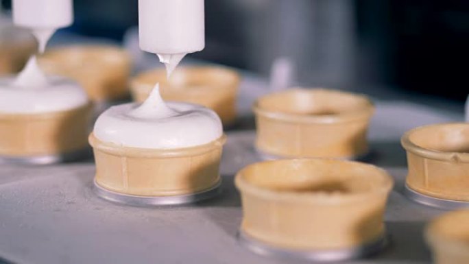工厂生产冰淇淋。用圣代填充晶片锥的过程。