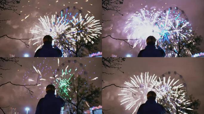 观看和拍摄烟花的男子的特写剪影在户外智能手机相机上爆炸