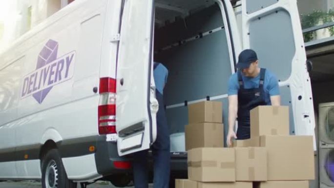 两名强壮的送货员装载装满纸箱的商用车。