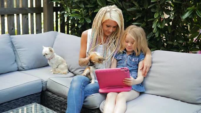 时髦的母亲和年幼的女儿在数字平板电脑上