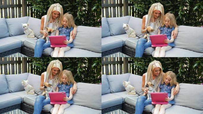 时髦的母亲和年幼的女儿在数字平板电脑上
