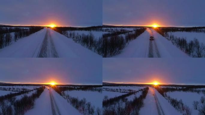 空中: 在拉普兰令人惊叹的冬日日落时，汽车在空旷的雪路上行驶