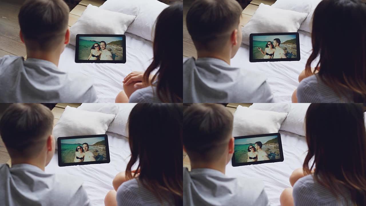 已婚夫妇正在使用平板电脑在skype上与朋友交谈，快乐的恋人在屏幕上笑着亲吻，背景是美丽的大海。视频