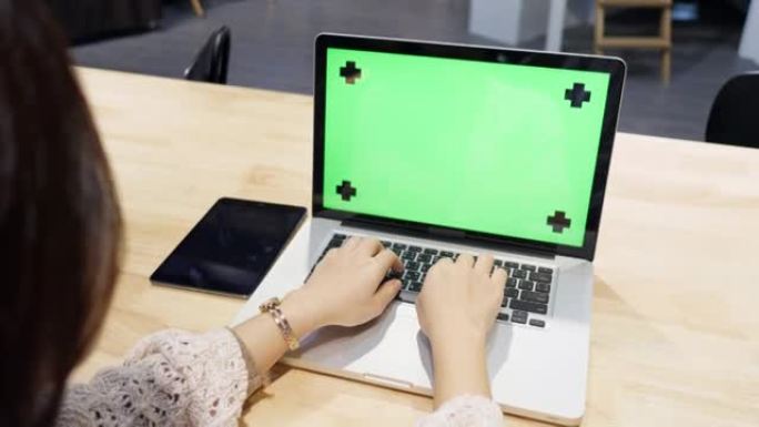 年轻女子用绿色屏幕打字笔记本电脑