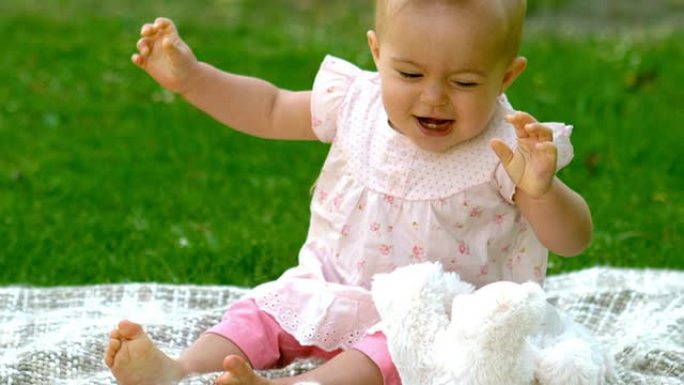 快乐的婴儿在毯子上的公园里笑