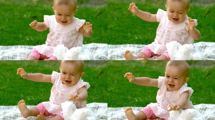 快乐的婴儿在毯子上的公园里笑