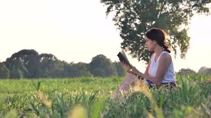 在阳光明媚的日子里，一个美丽的年轻学生女孩在大自然中读书