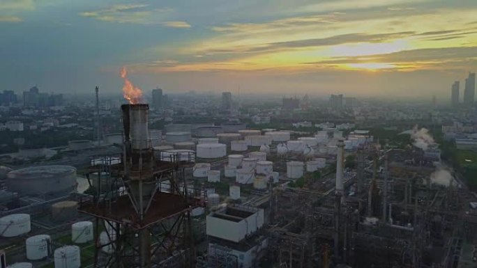 城市日出时燃烧火炬的化工或炼油厂的鸟瞰图