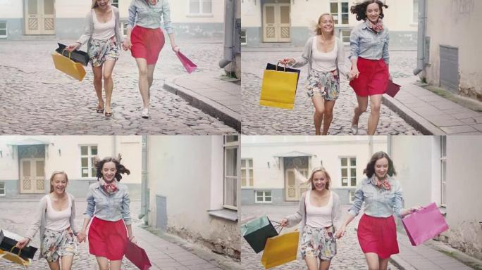 两个快乐的女孩在欧洲小镇的街道上背着购物袋奔跑