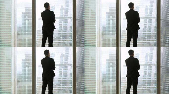 后视图在商人西装站在全长度窗口附近