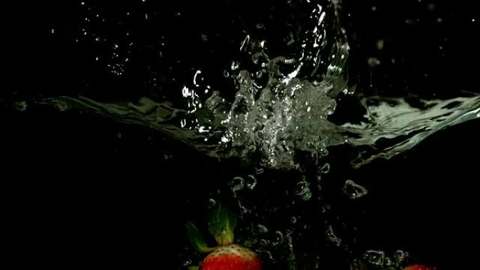草莓落在黑色背景上的水中