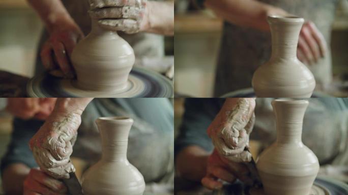 在陶工的轮子上旋转半成品陶瓷罐的特写镜头，用专业工具将粘土成型。创造了eathenware和传统陶器