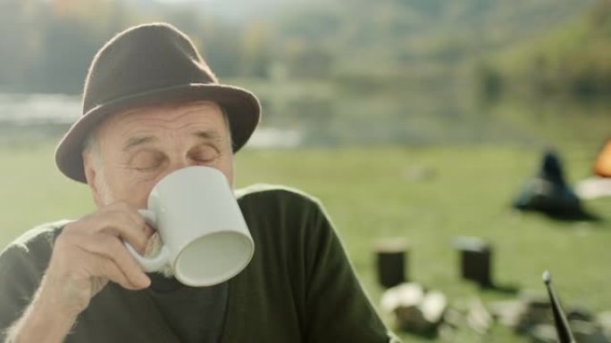 老人在湖边露营时喝咖啡