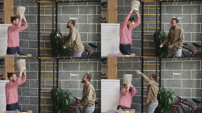 两个多种族的男人玩篮球游戏，在现代办公室的垃圾桶里扔纸