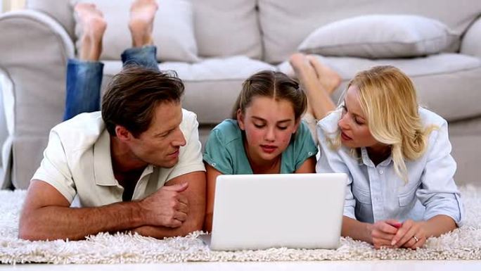 父母和女儿在地板上愉快地使用笔记本电脑