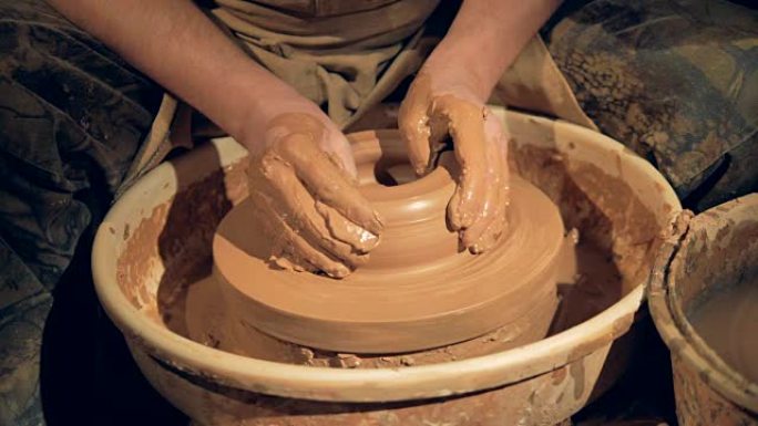 陶艺家的手在轮子上做一个宽而低的碗。