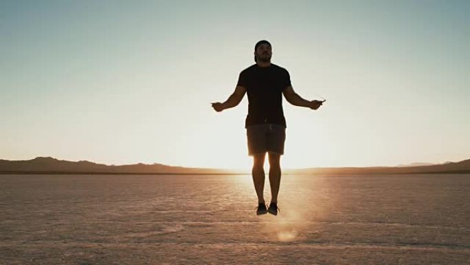慢动作运动员在日落时在沙漠外面锻炼跳绳