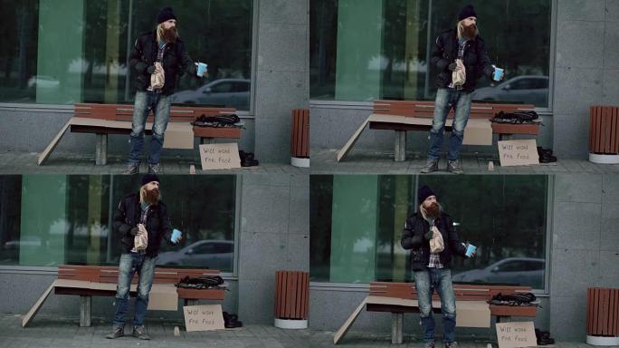 醉酒的无家可归的人，带着纸板和酒精的标志，站在人行道上的长凳旁乞讨钱